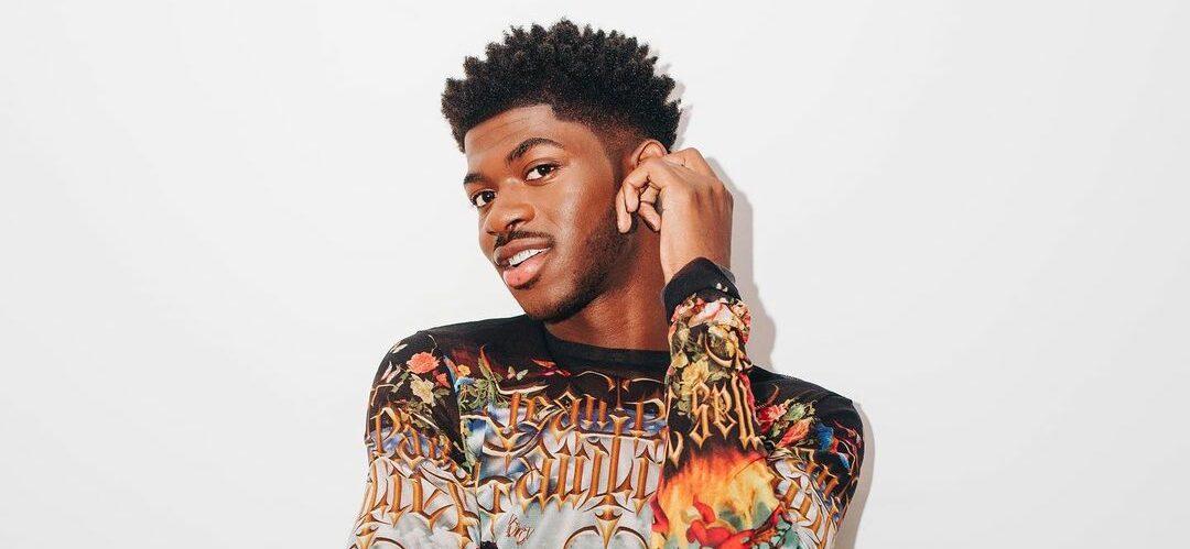 A photo showing Lil Nas X sporting a body hug multi colored outfit.