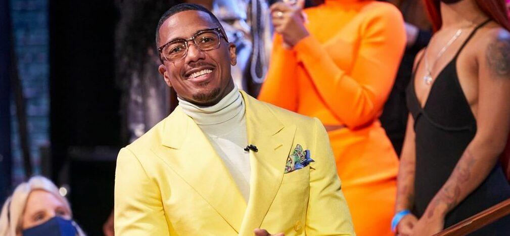 A photo showing Nick Cannon in a yellow color suit paired with a creme turtle neck sweatshirt.