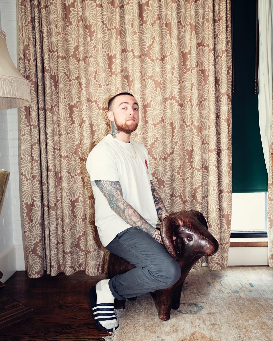 A photo showing Mac Miller in a white shirt and black pant.