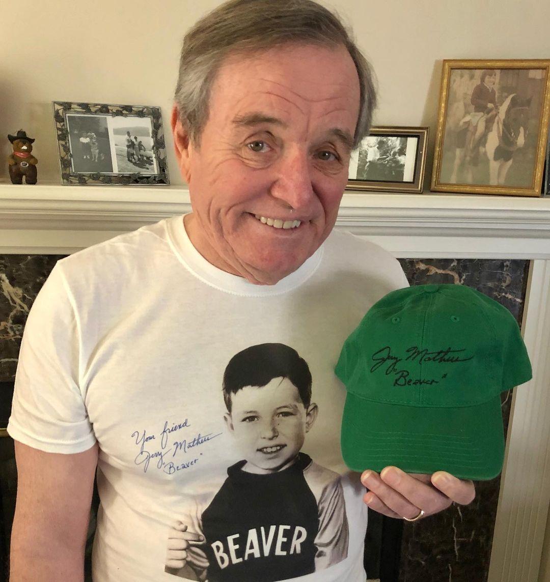 A photo showing Jerry Mathers sporting a white shirt and holding a green cap.