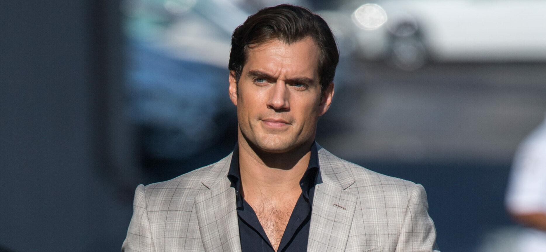 Henry Cavill at 'Kimmel' sporting a gray striped suit and pant paired with a black inner T-shirt.