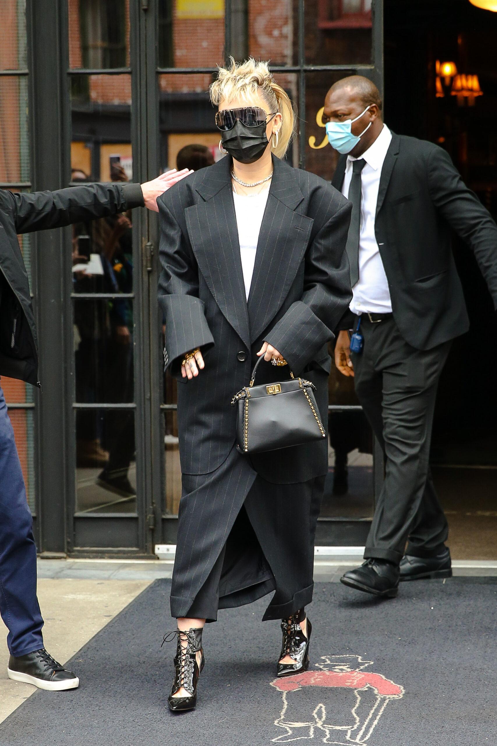 Miley Cyrus seen wearing a long black coat as leaving her hotel in NYC