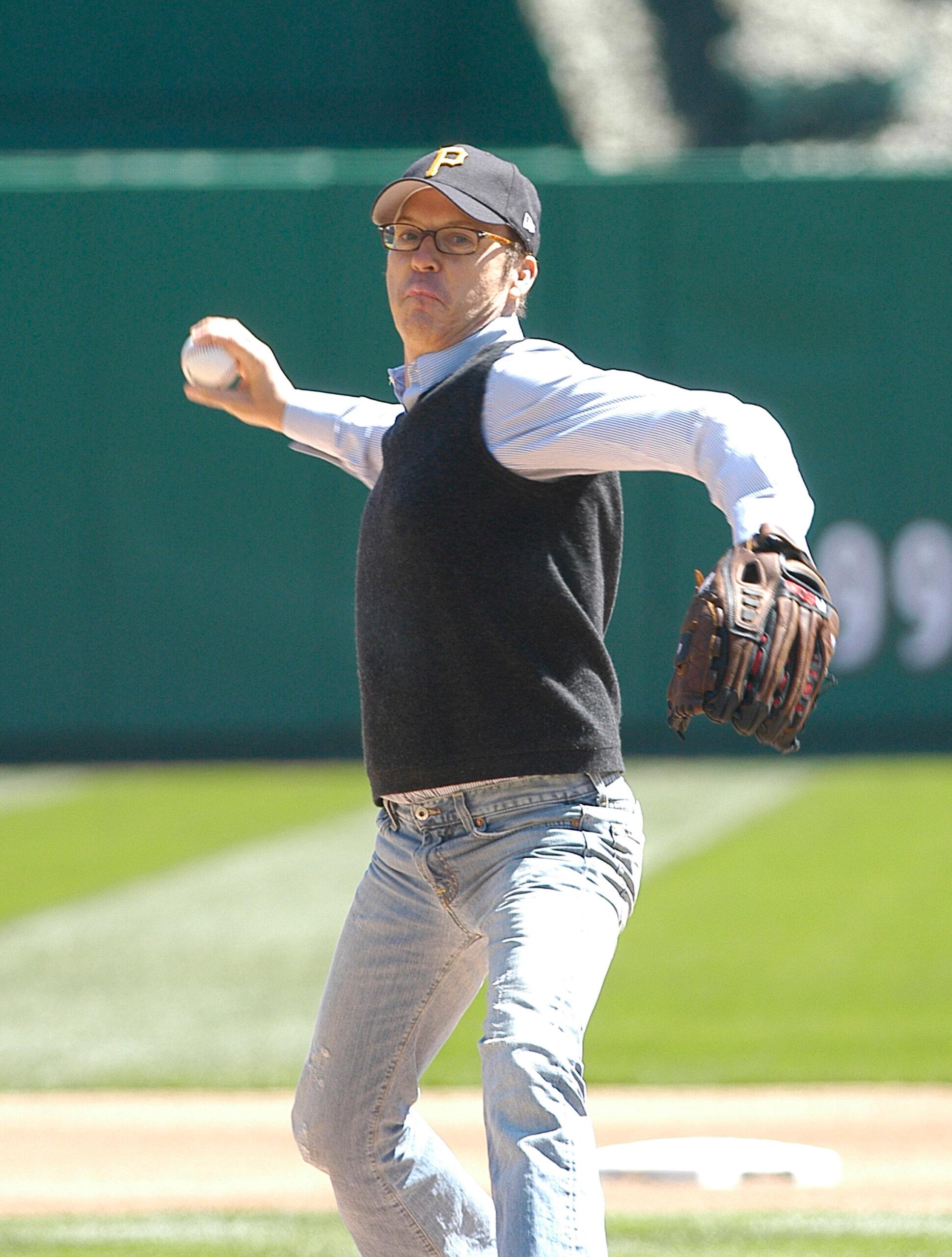 A photo of Michael Keaton on a field about to throw a ball.