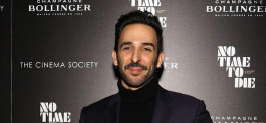 A photo showing Amir Arison in a black suit and matching inner T-shirt at an event.