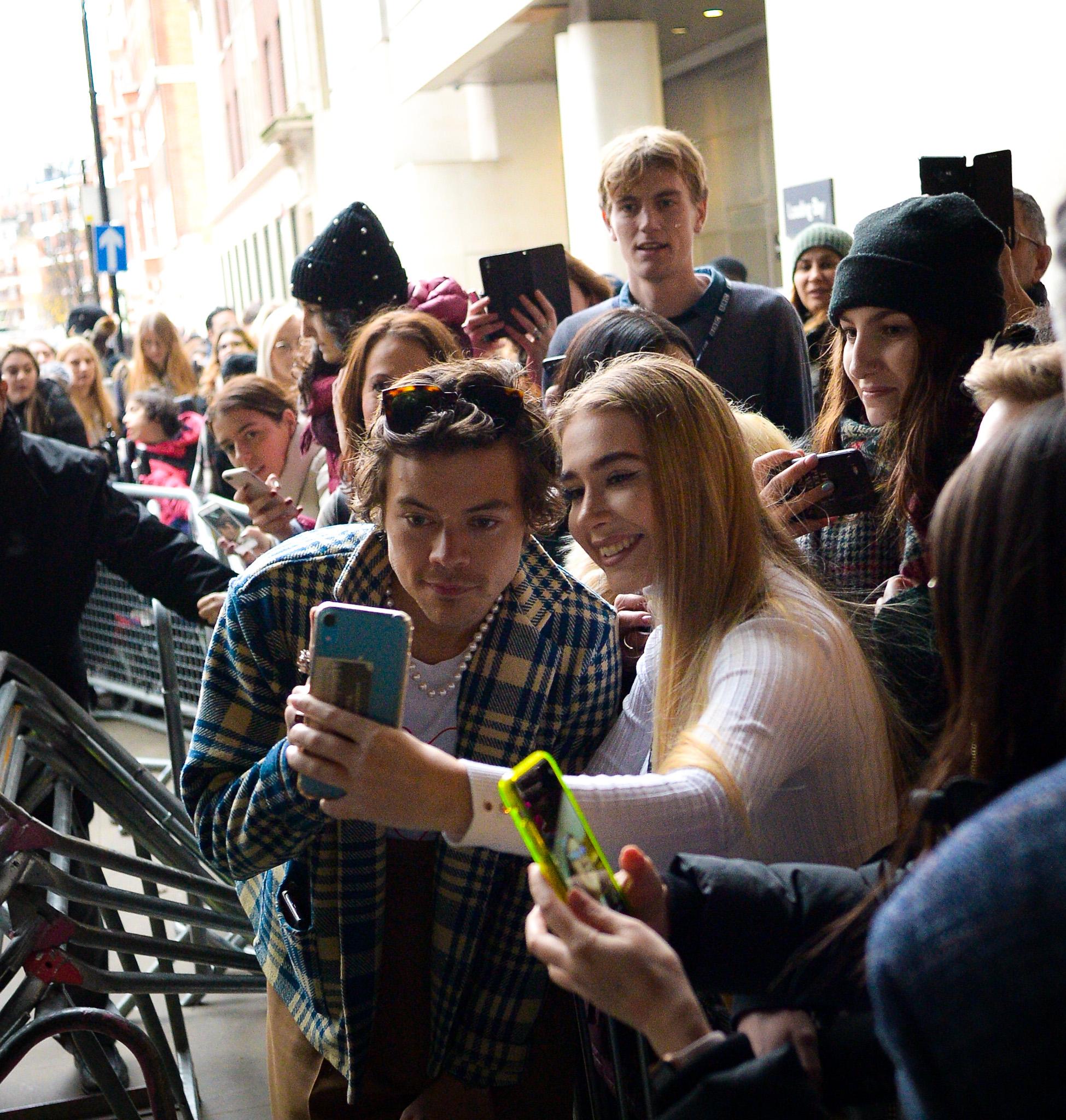 Harry Styles taking a selfie with a fan