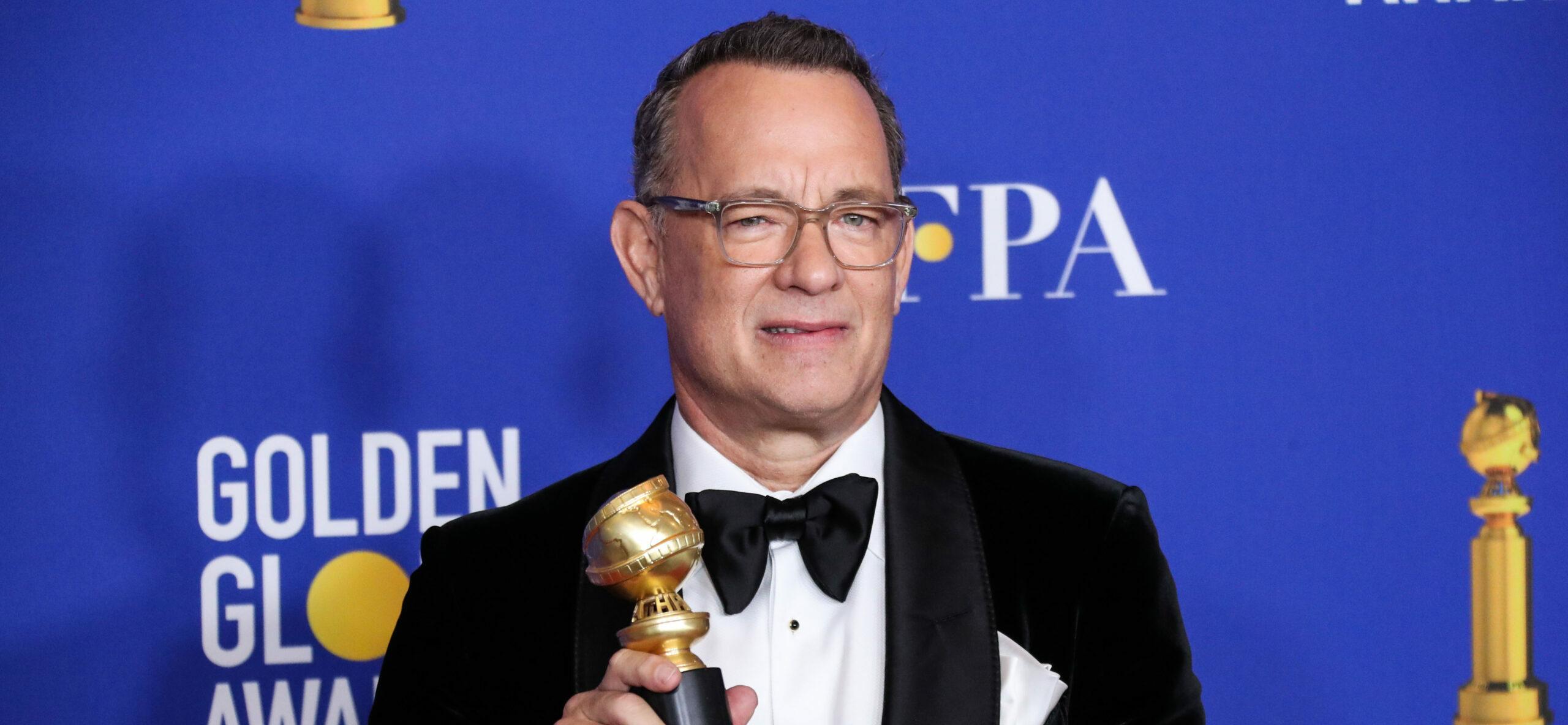 Tom Hanks holding a Golden Globes Award with a huge smile on his face.