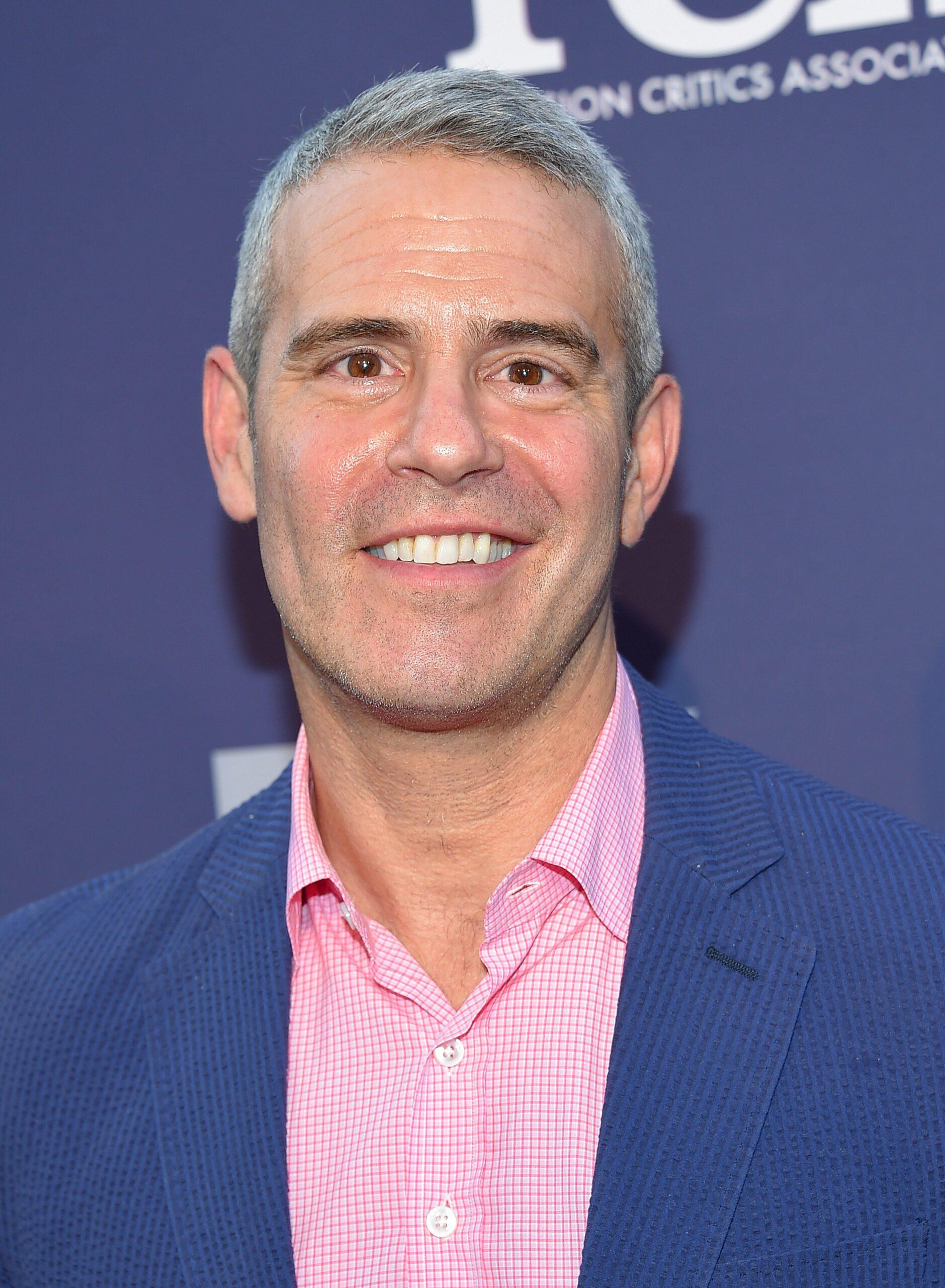 Andy Cohen sports a blue suit and pink inner T-shirt.