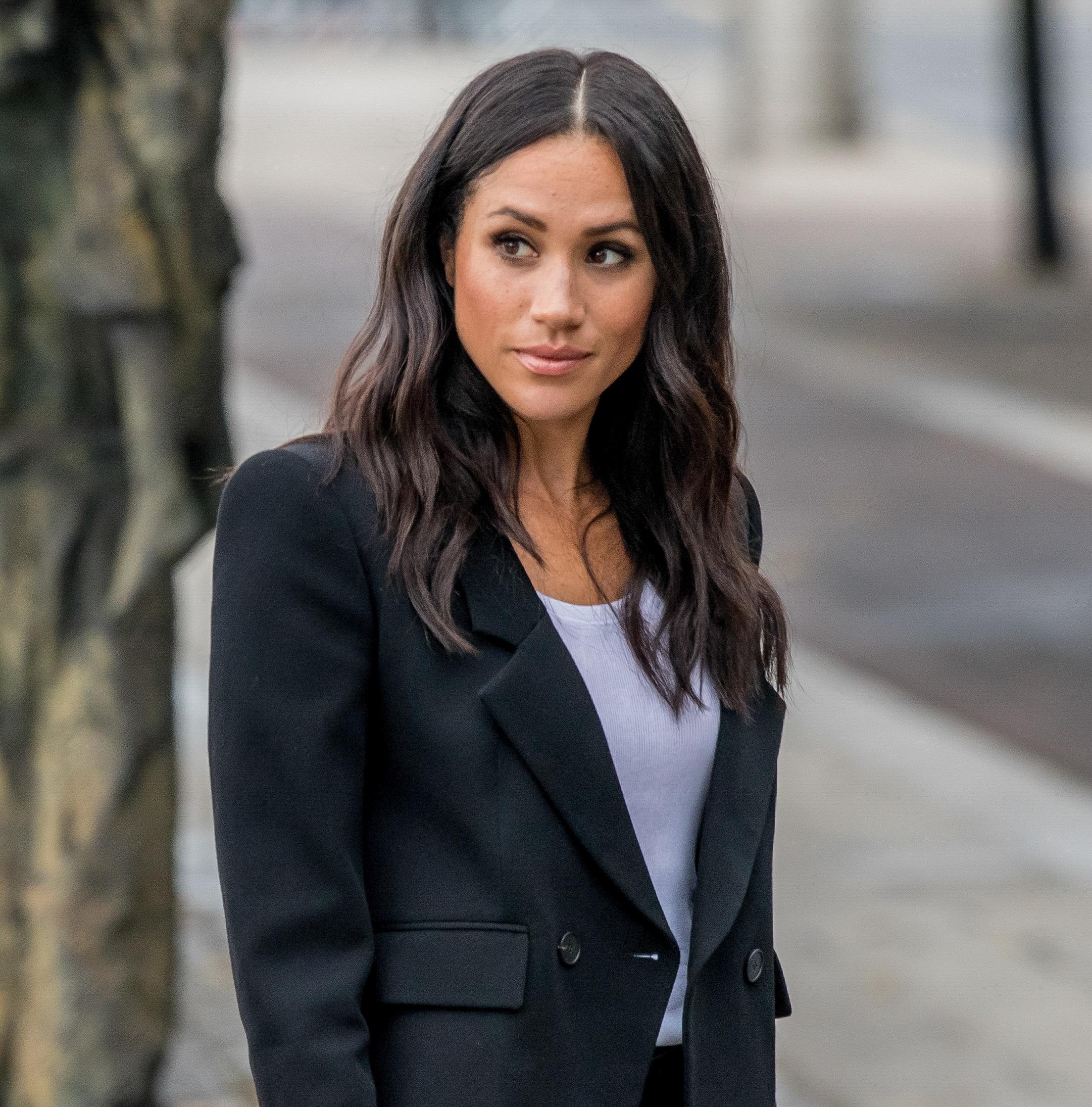 Meghan Markle out and about in a black suit and white inner outfit.