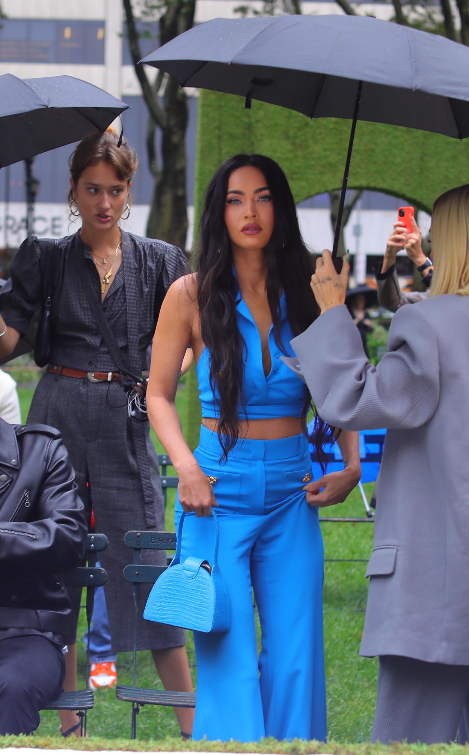 Megan Fox stuns in blue as she stares into the cameras while holding an umbrella in the rain during the Moschino fashion show held outside during fashion week in NYC