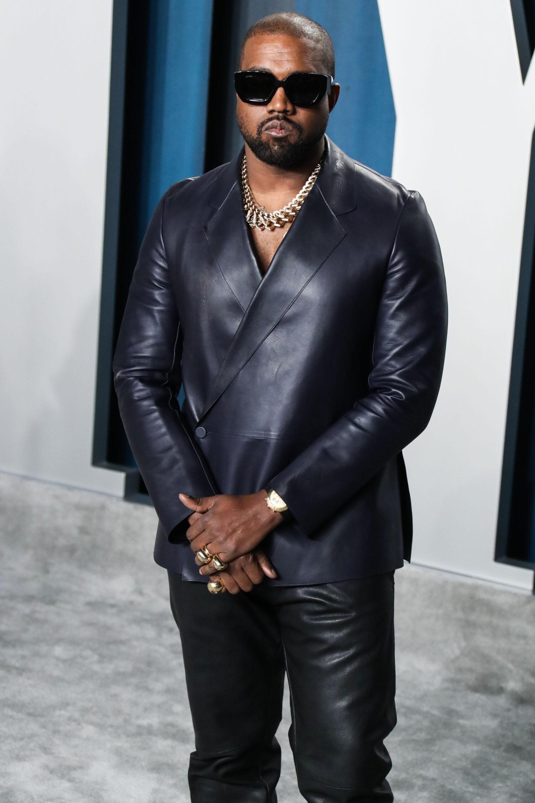 Kanye West rocking a black leather jacket and pant, with dark shades at an event.