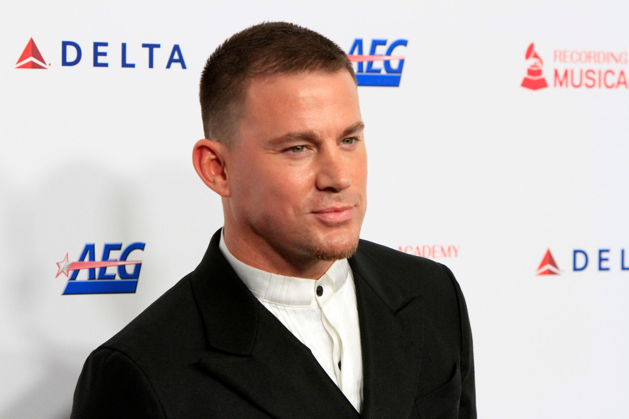 A photo of Channing Tatum at en event sporting a black suit and white inner T-shirt.