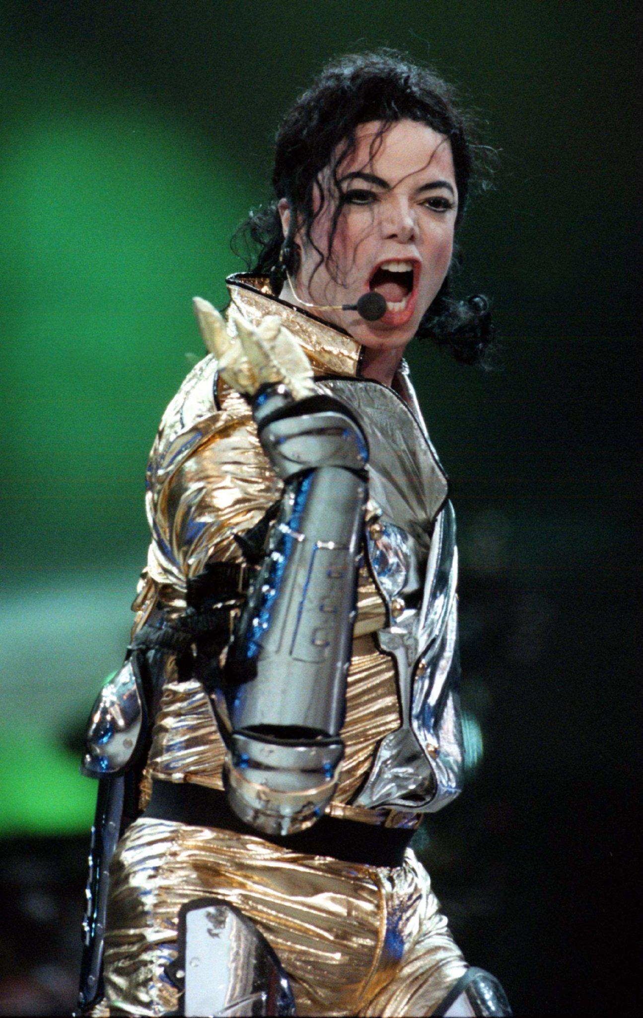 Micheal Jackson performing on stage in a golden outfit.