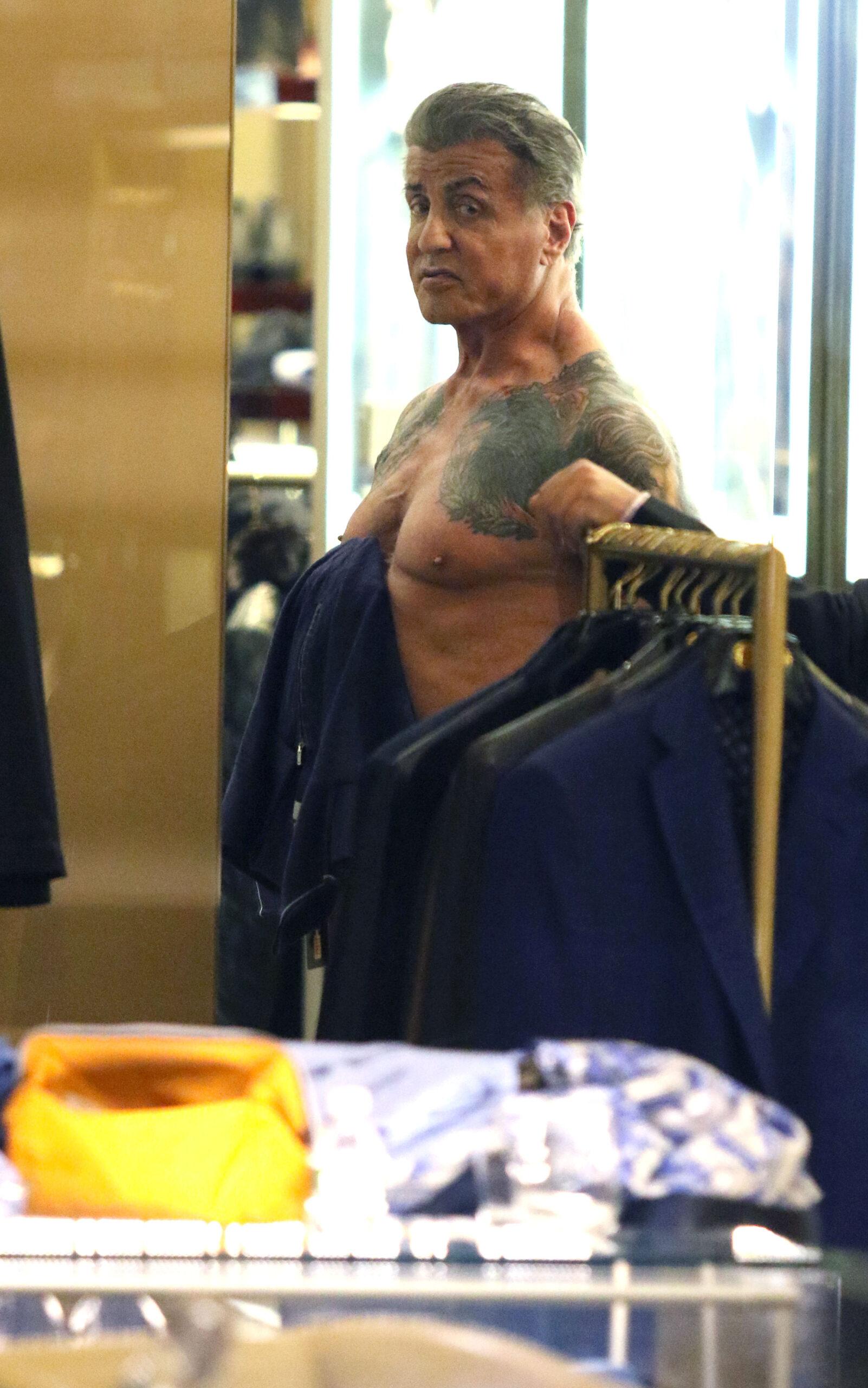 Sylvester Stallone goes shirtless as he shows off muscular physique and heavily tattooed back and chest while shopping in New York City.