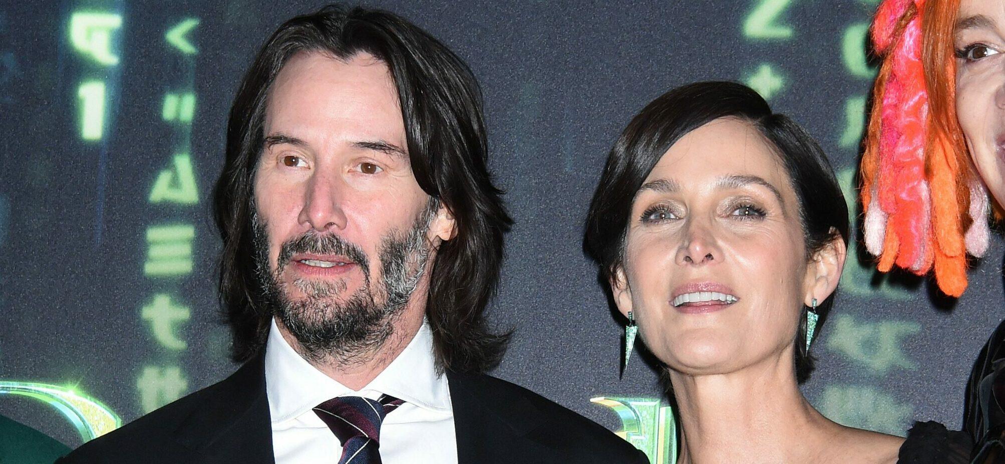 Keanu Reeves and Carrie-Anne Moss posing for the camera.