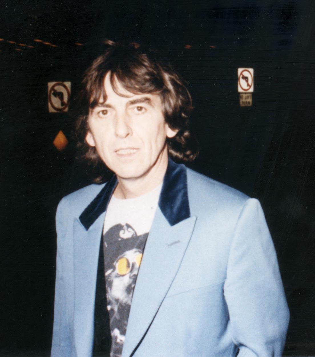 A throwback photo of George Harrison in a blue suit at an event.