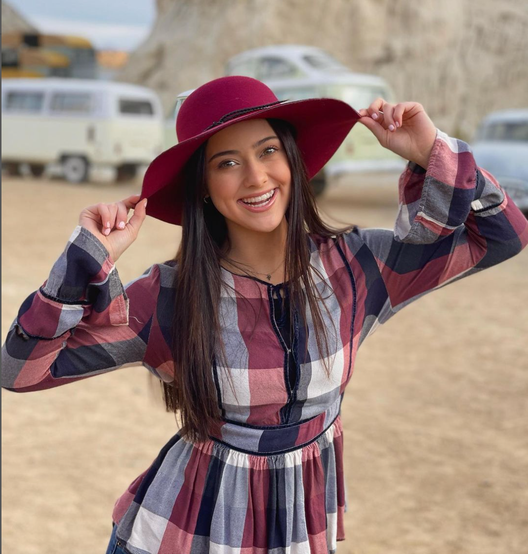 Kailia Posey in checkered dress and red hat