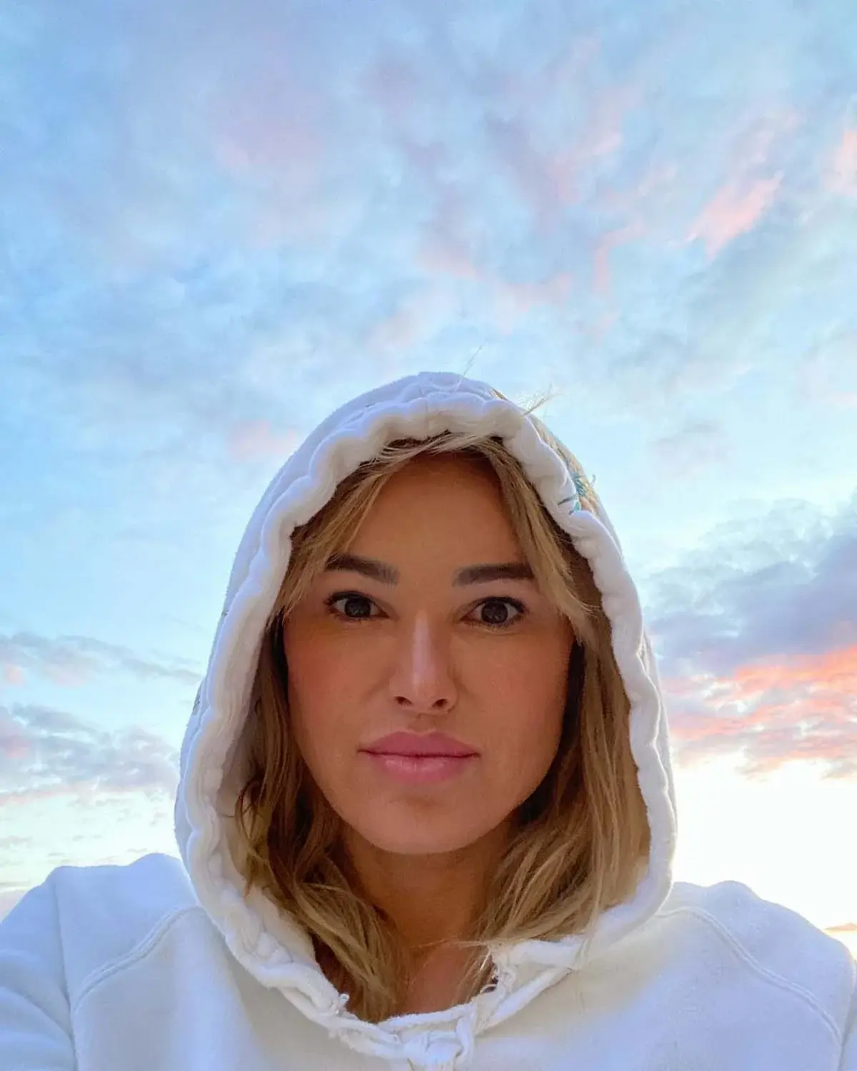 woman looking down at camera wearing a hoodie