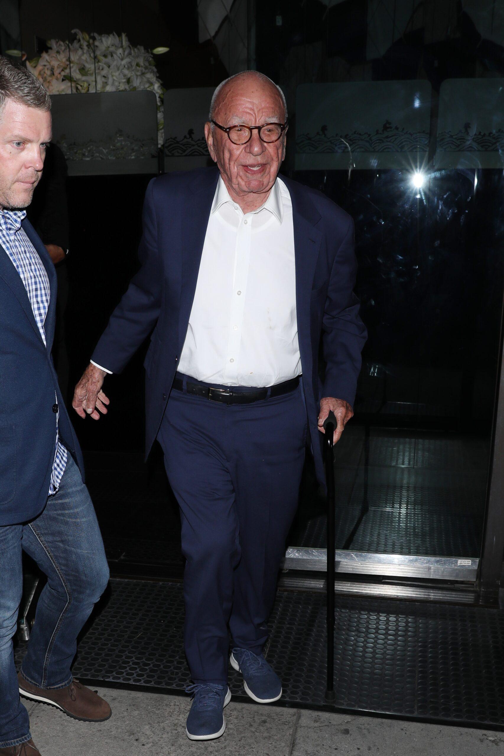 Rupert Murdoch walks with a cane in hand as he leaves Mr Chow restaurant after having dinner