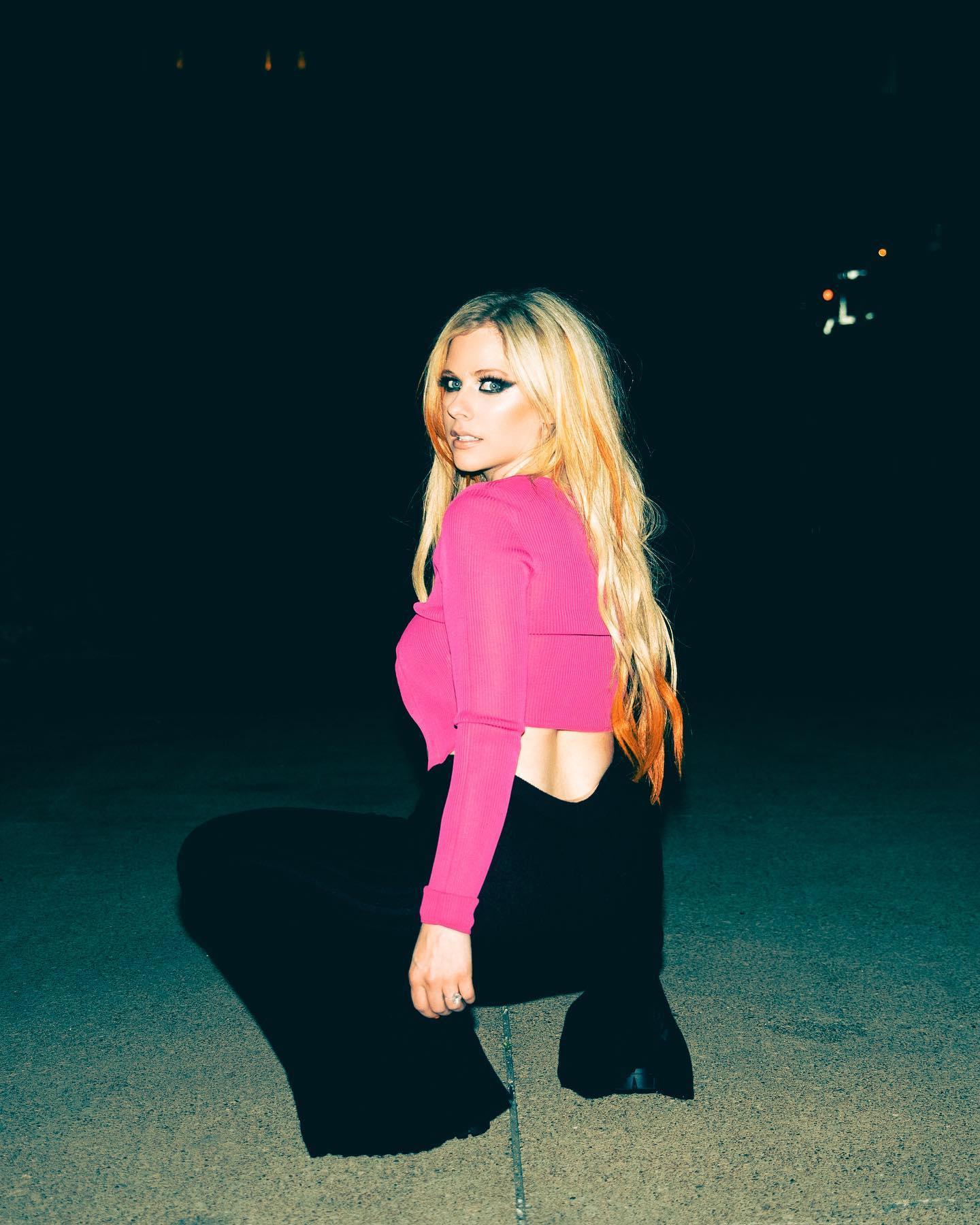 Avril Lavigne in black slacks and a skimpy pink top