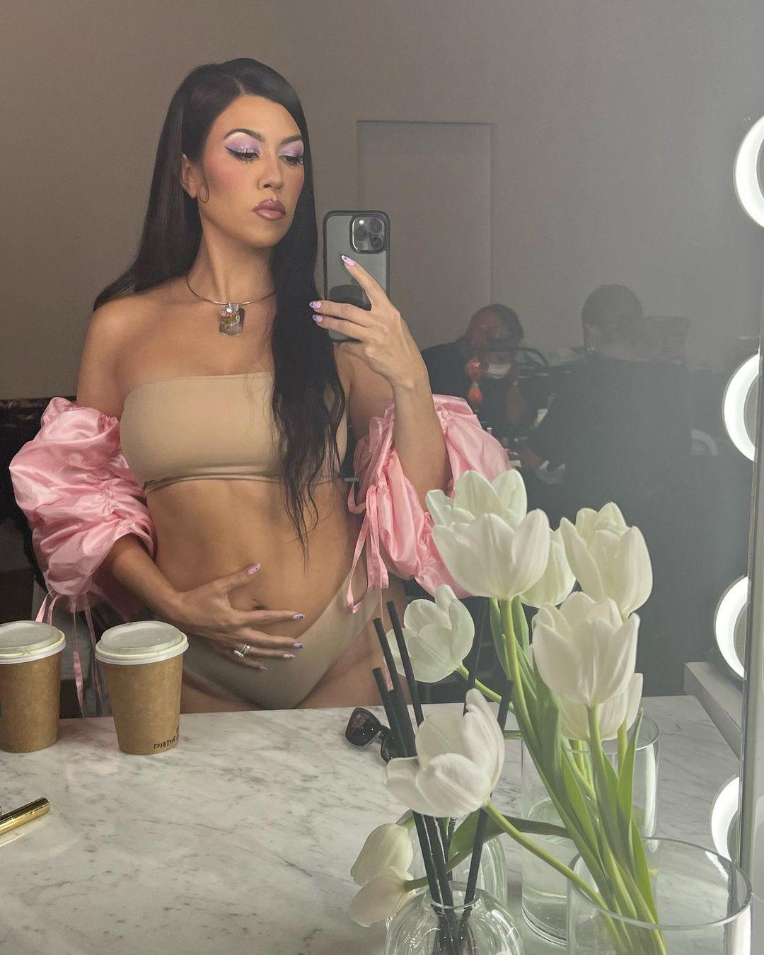 Kourtney Kardashian touches her belly