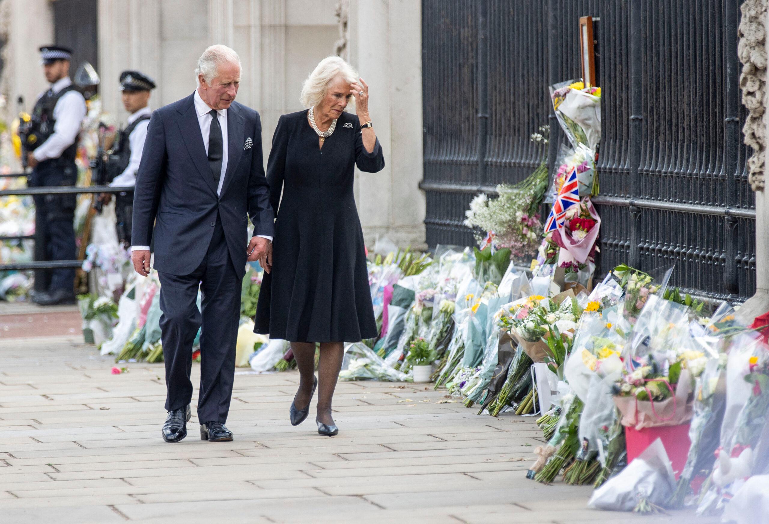 O Rei Carlos III e a Rainha Consorte Camilla observam os tributos florais deixados para a Rainha Elizabeth II do lado de fora do Palácio de Buckingham, no centro de Londres