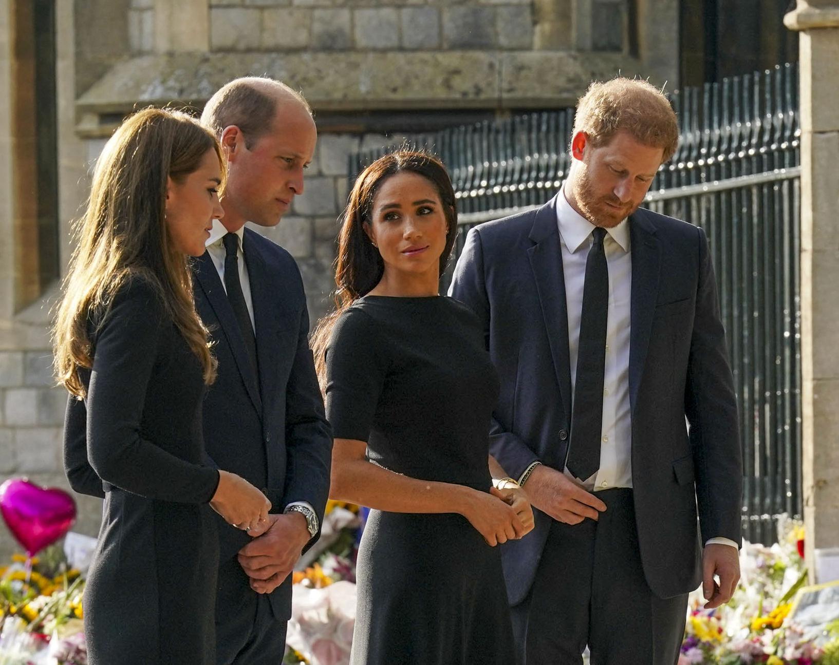 The Prince and Princess of Wales with Prince Harry and Meghan look at flowers and sympathy cards left for the Queen