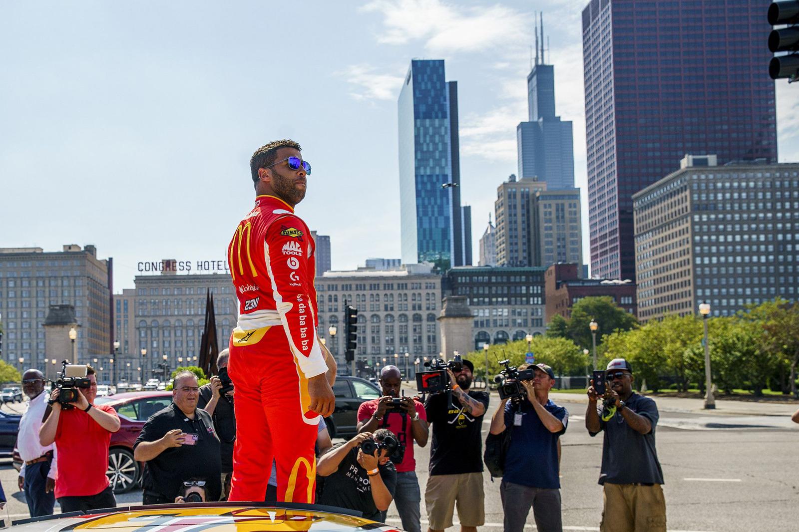 NASCAR driver Bubba Wallace stands on a race car after driving through Grant Park after Mayor Lori Lightfoot announced the city will host a NASCAR street race next year, July 19, 2022 in Chicago.