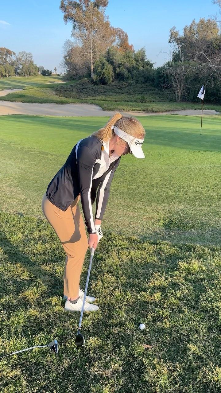 Grace Charis plays golf in a jacket
