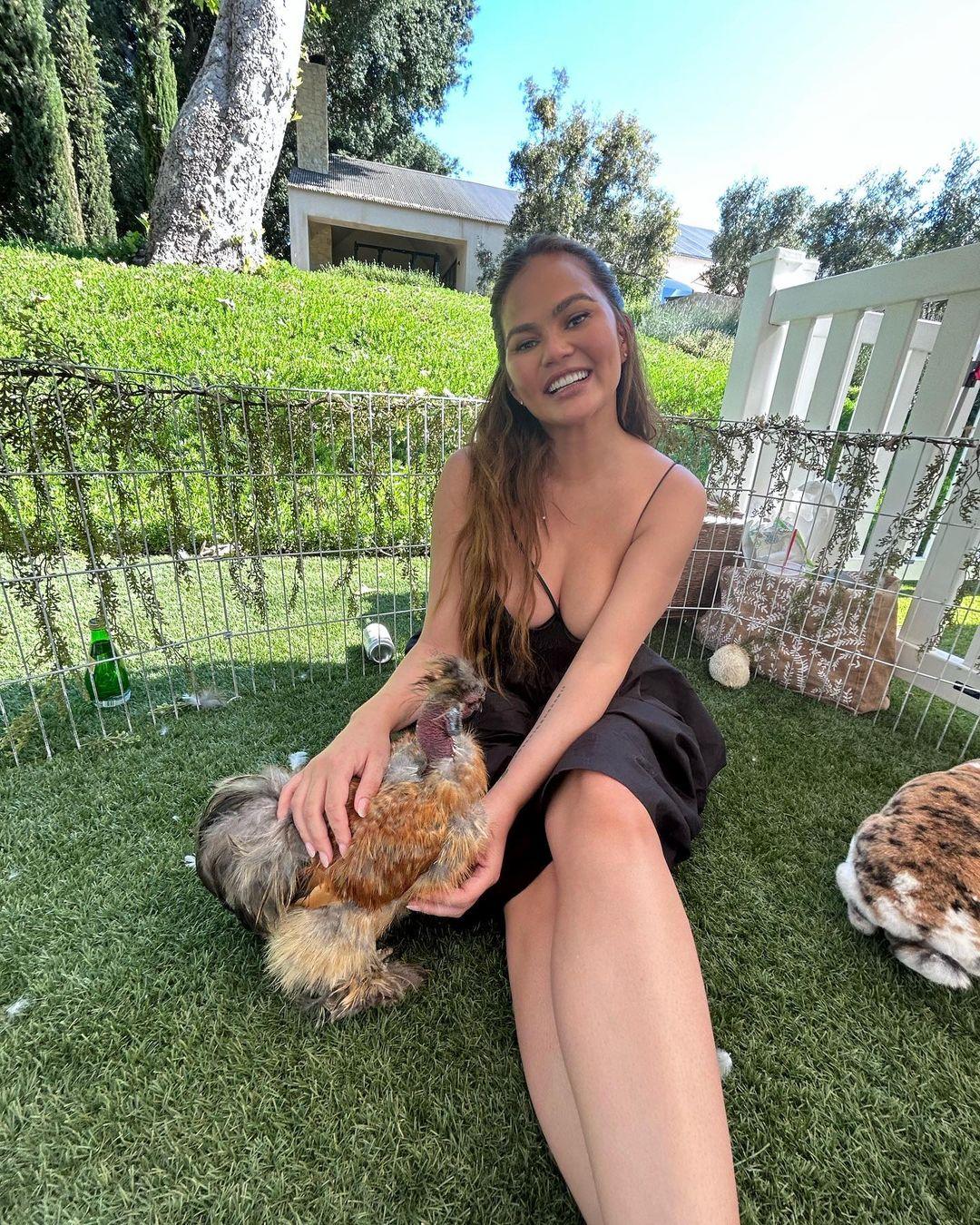 Chrissy Teigen flaunts cleavage while playing with animals