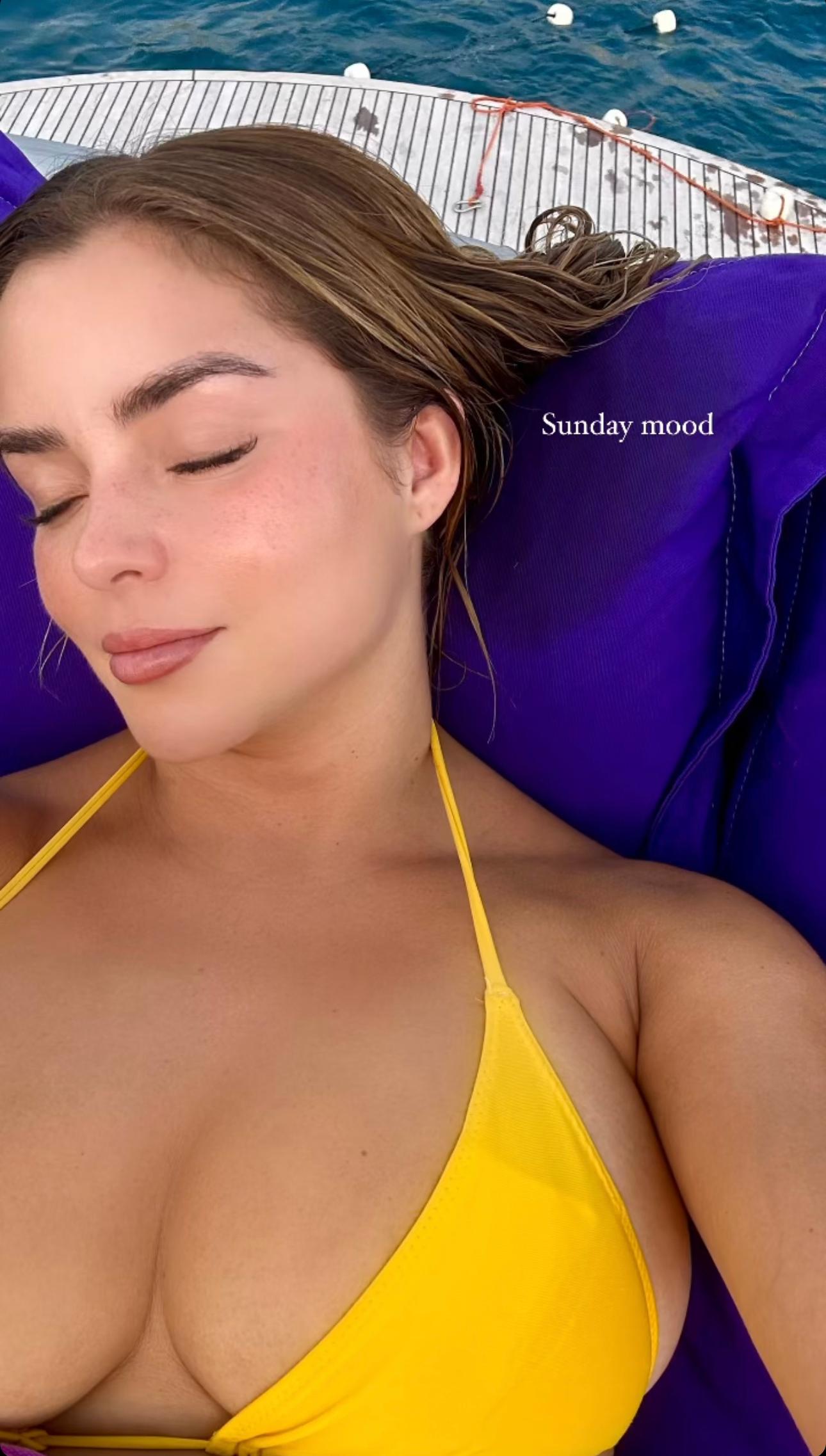 Demi Rose takes a selfie while wearing a yellow bikini top.