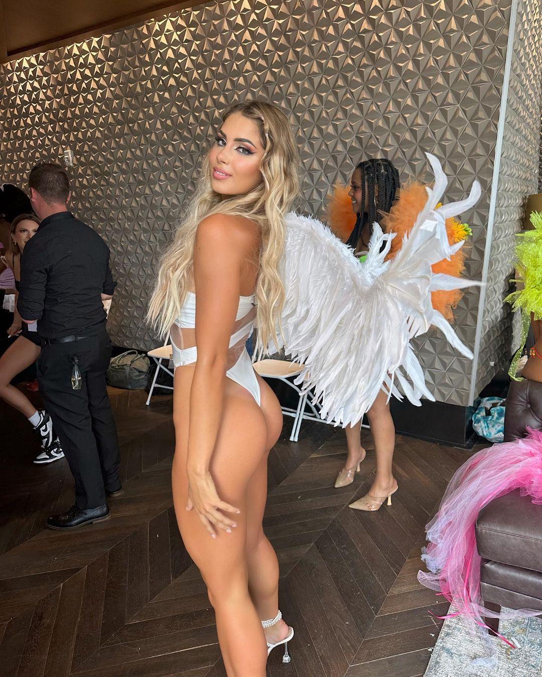 Andreea Dragoi posing for the camera in a white swimsuit and faux wings.