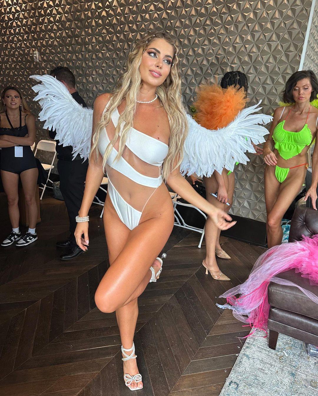 Andreea Dragoi posing for the camera in a white swimsuit and faux wings.