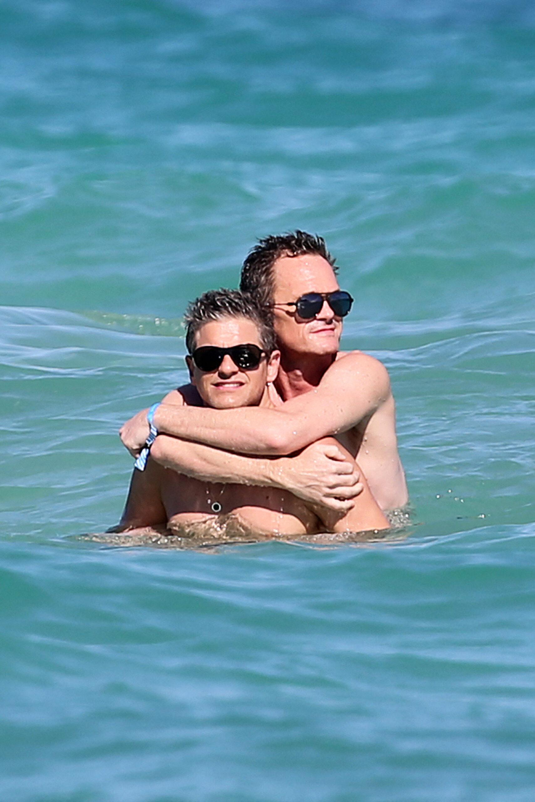 Neil Patrick Harris and David Burtka show off their beach bodies and indulge in some PDA as they hit the beach in Miami.