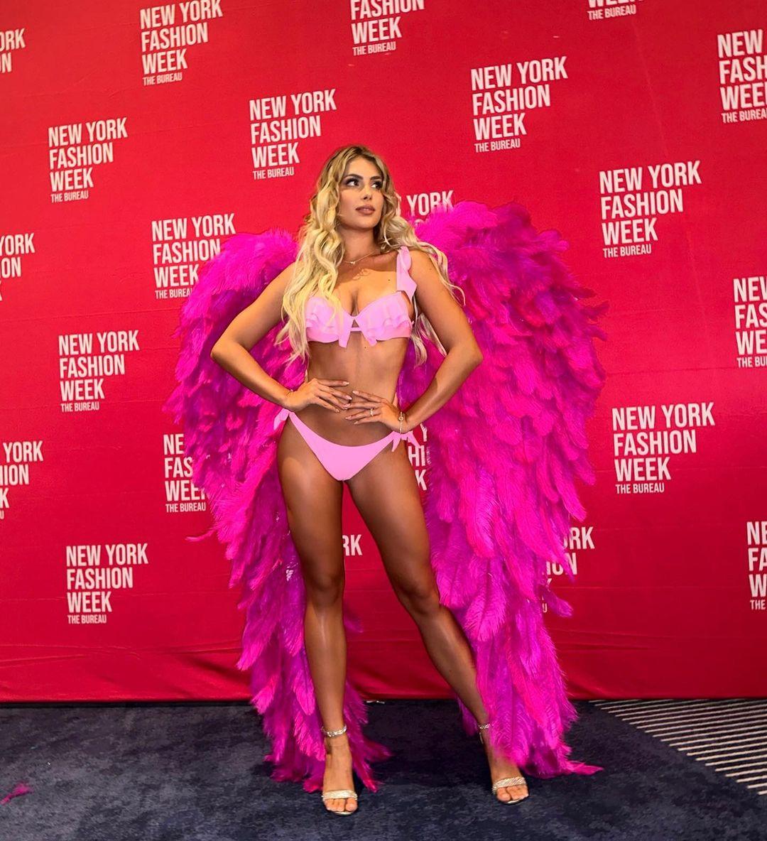 Andreea Dragoi walks at New York Fashion Week in a pink swimsuit and angel wings.