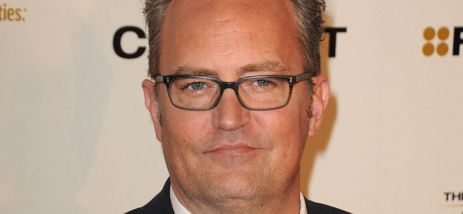 Matthew Perry smiling while wearing glasses