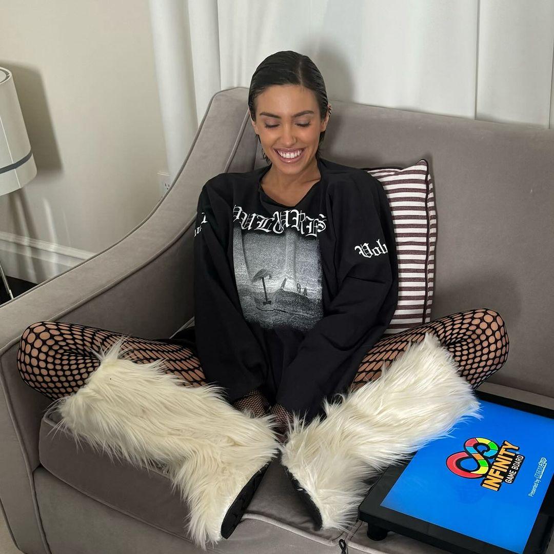 Kanye West's Wife Bianca Censori smiling with her eyes closed on a couch