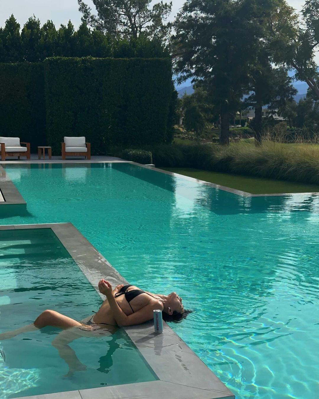 Kylie Jenner relaxing in the pool in hr black bikini.