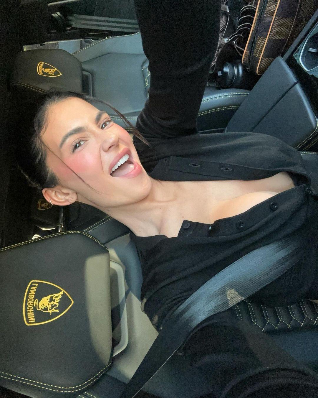Kylie Jenner snaps a selfie inide her lambo while wearing a plunging black top.