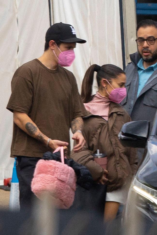 Ariana Grande apresenta uma figura casual com um top rosa com gola alta quando é vista pela primeira vez no set de Wicked ao lado de seu marido Dalton Gomez em Londres