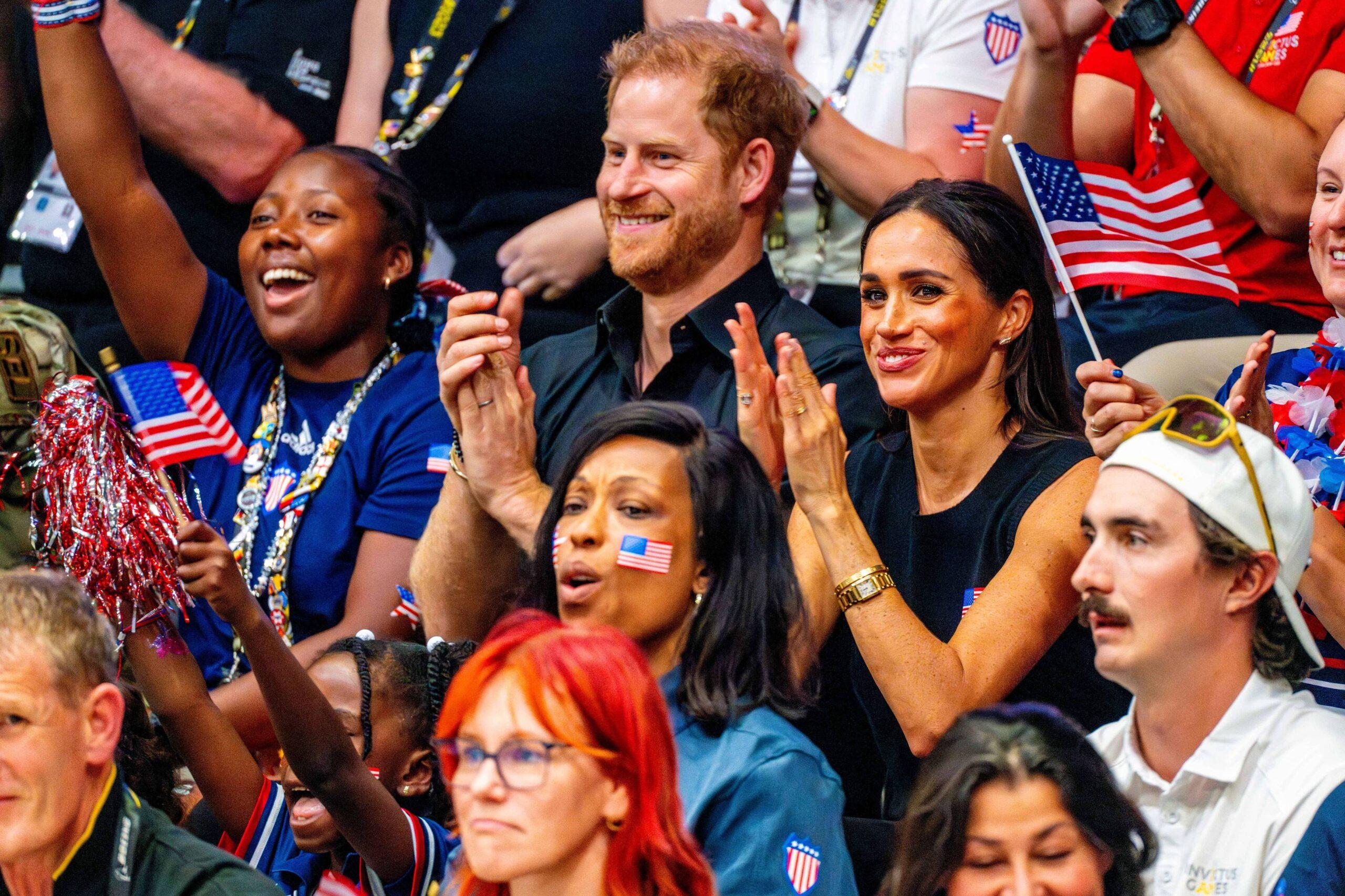 Príncipe Harry e Meghan Markle sorrindo e batendo palmas