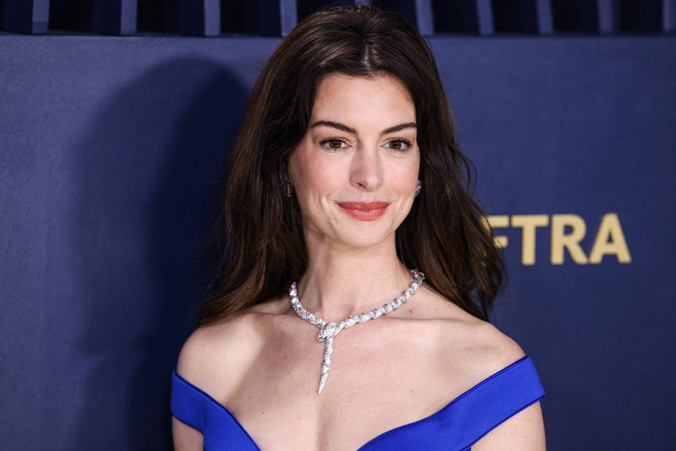 Anne Hathaway em vestido azul posa para a câmera
