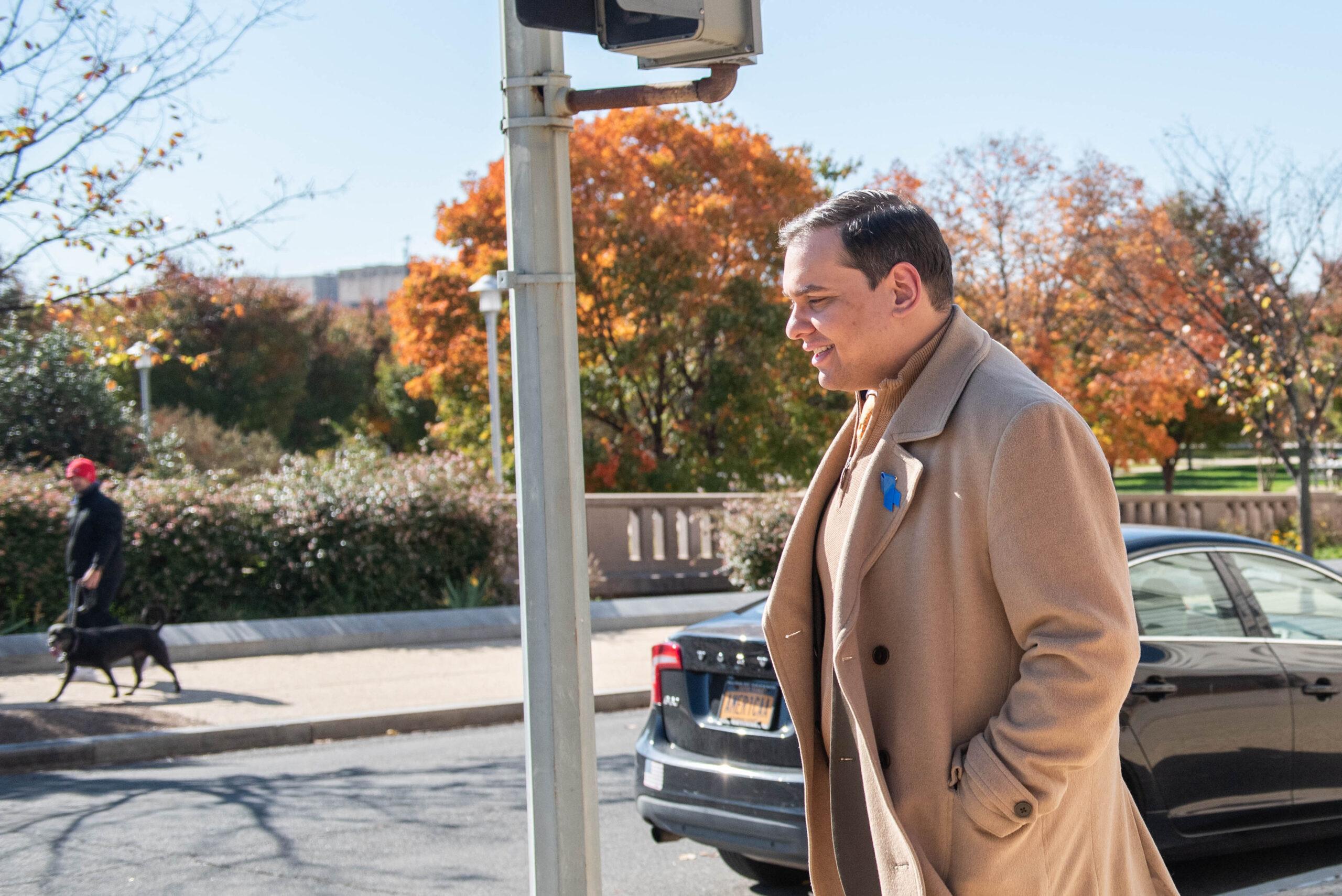 United States Representative George Santos (Republican of New York) has an aide cover his face as he exits his office.