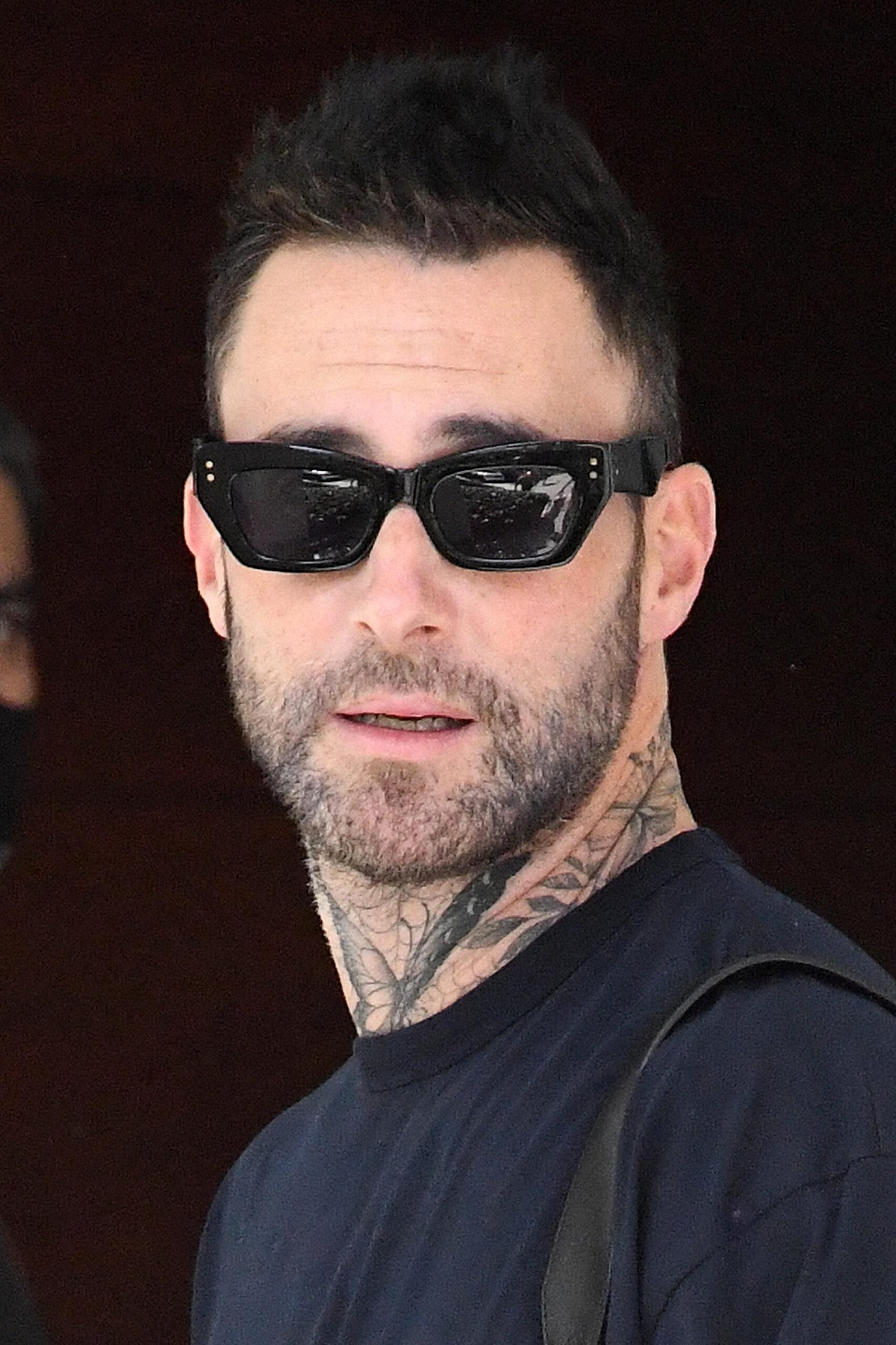 Adam Levine prova que sua nova tatuagem no rosto foi apenas temporária quando ele é visto saindo de seu hotel com sua esposa Behati Prinsloo em Miami