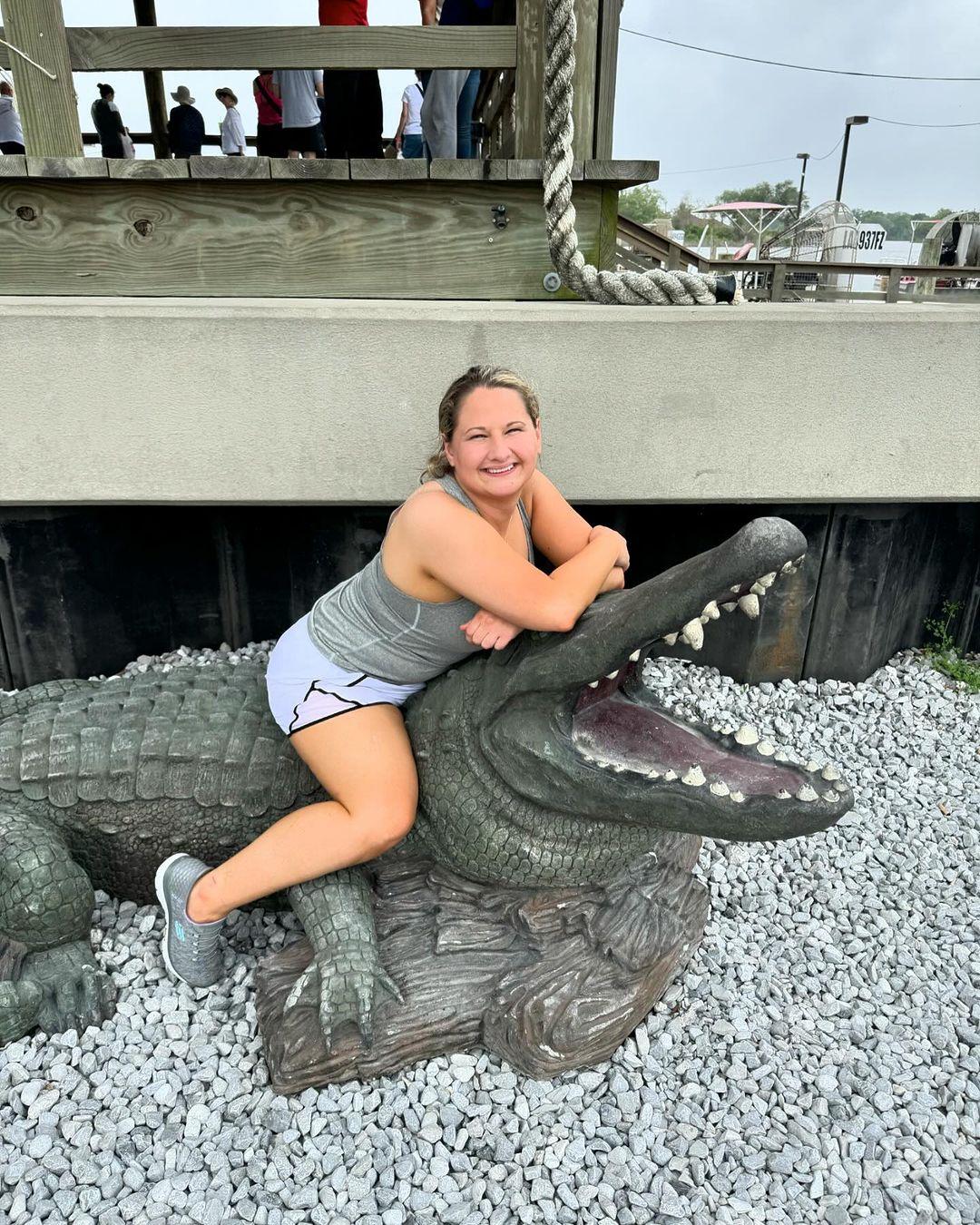 Cigana Rose Blanchard sentada em estátua de jacaré