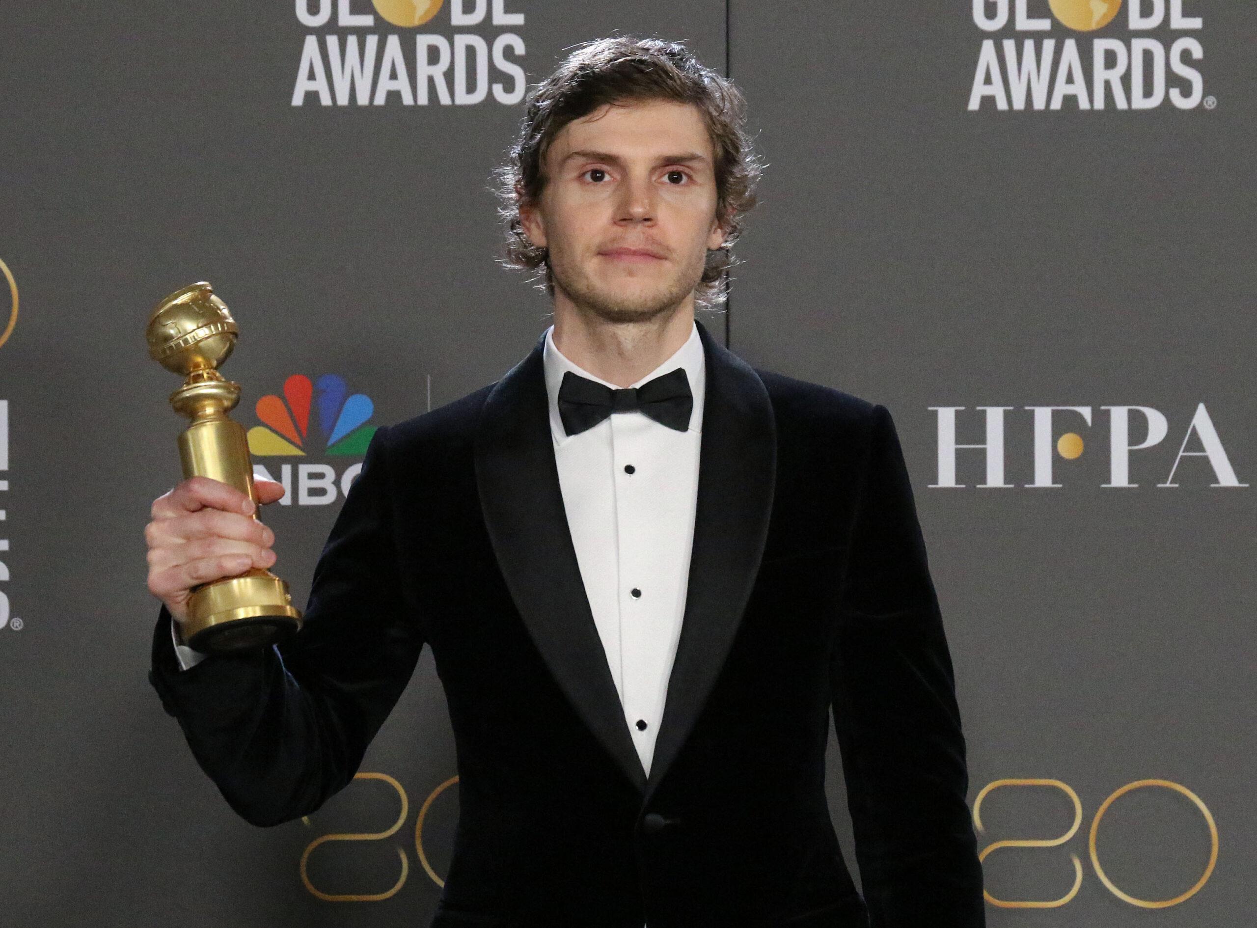 Evan Peters holding a Golden Globe