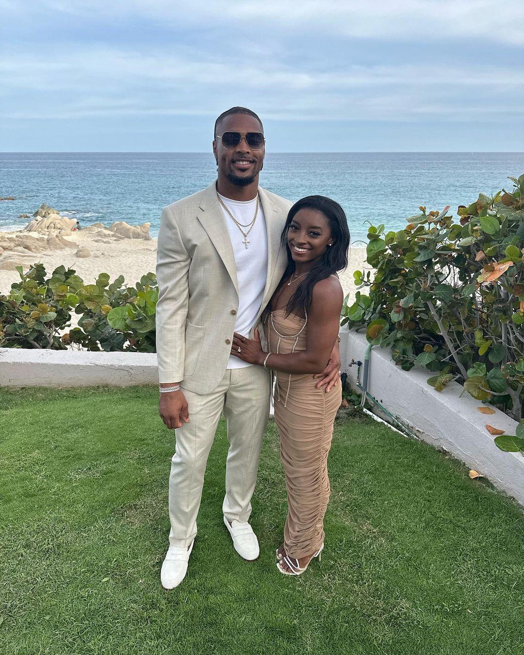 Jonathan Owens and Simone Biles posing in front of the beach