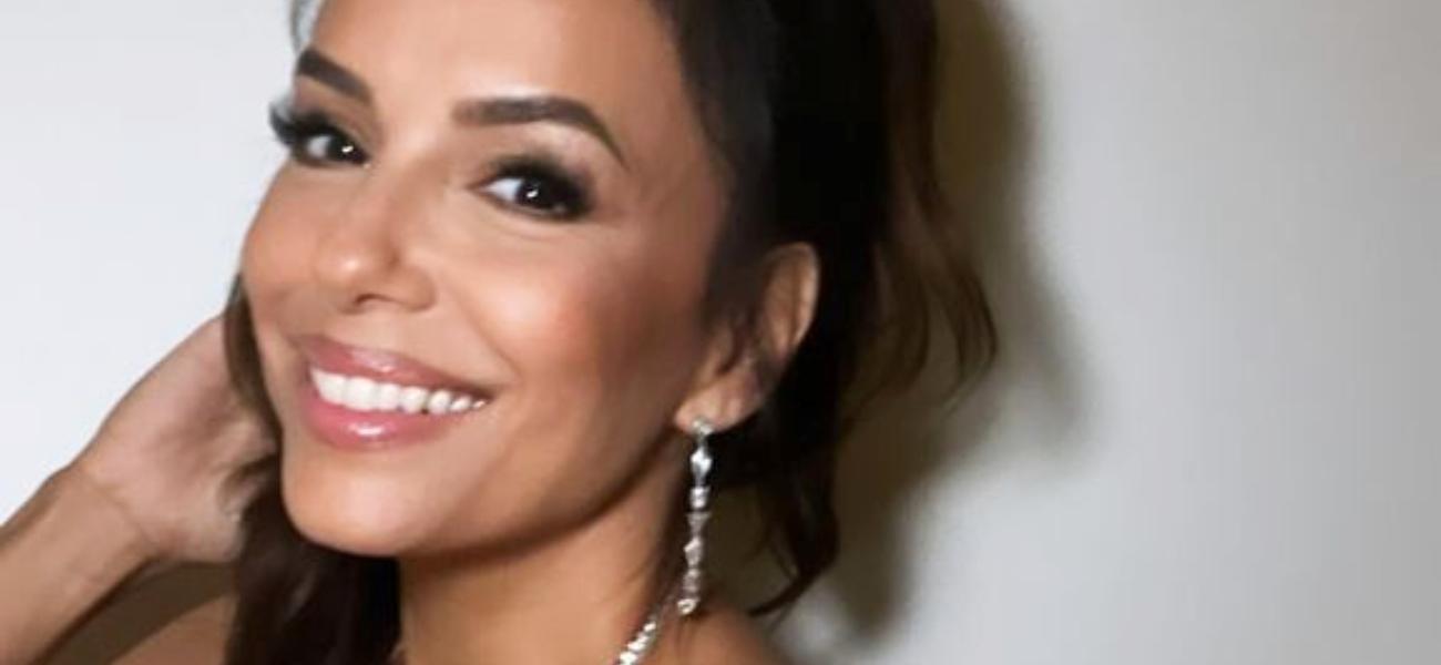 Eva Longoria smiles by a wall