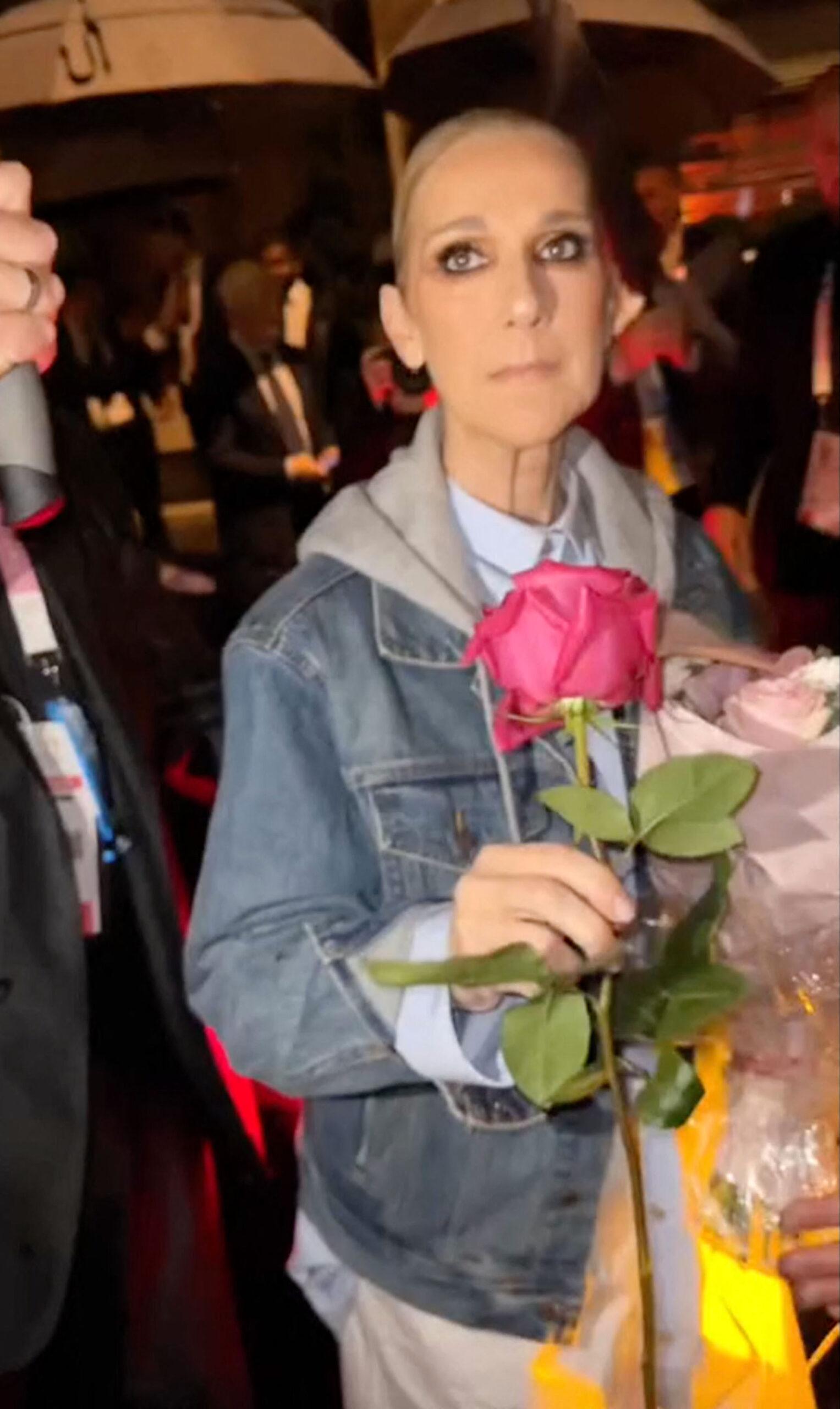 Celine Dion parece emocionada ao receber uma rosa de um fã após se apresentar na cerimônia de abertura das Olimpíadas