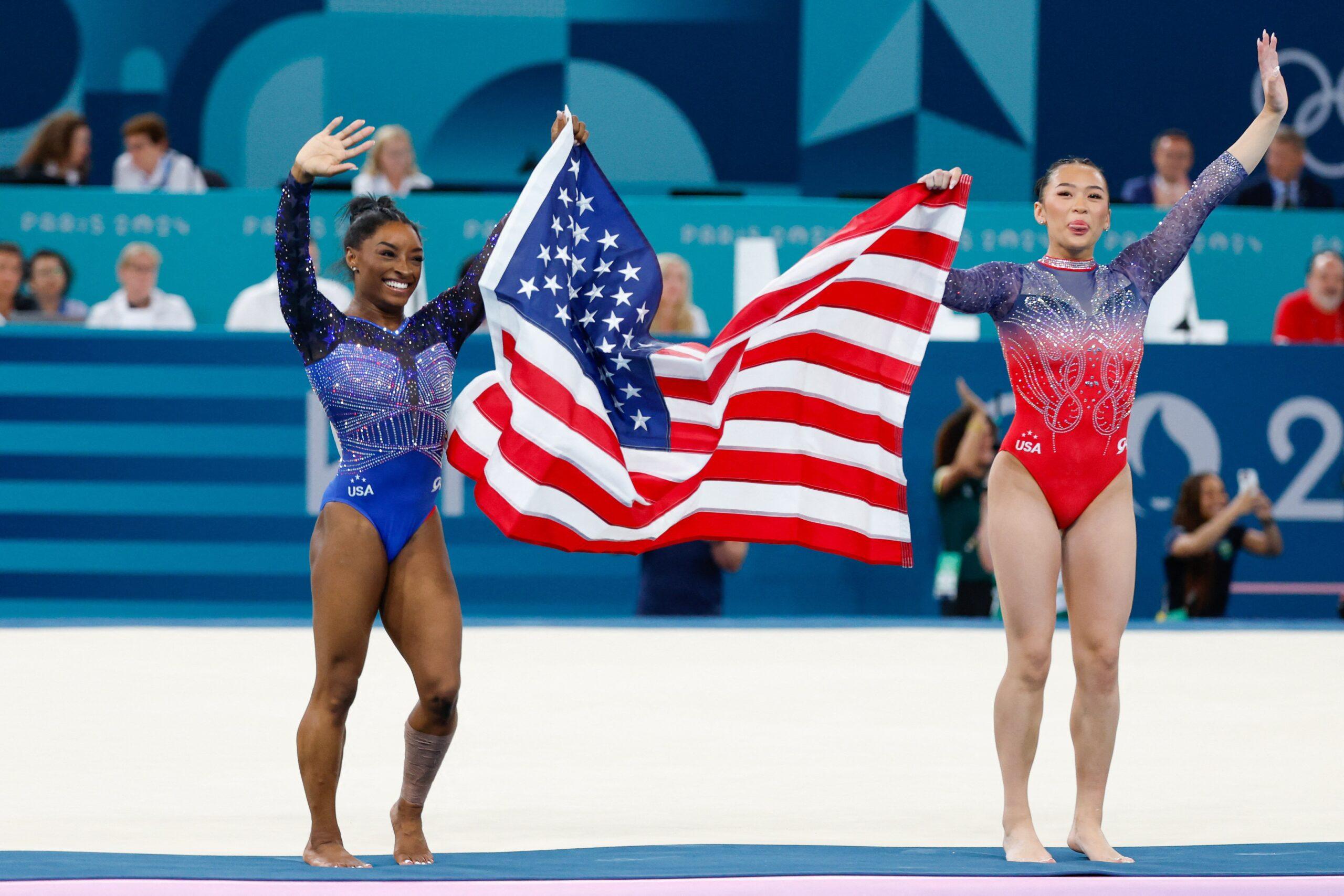 Simone Biles e Suni Lee segurando a bandeira da América nas Olimpíadas de Paris em 2024