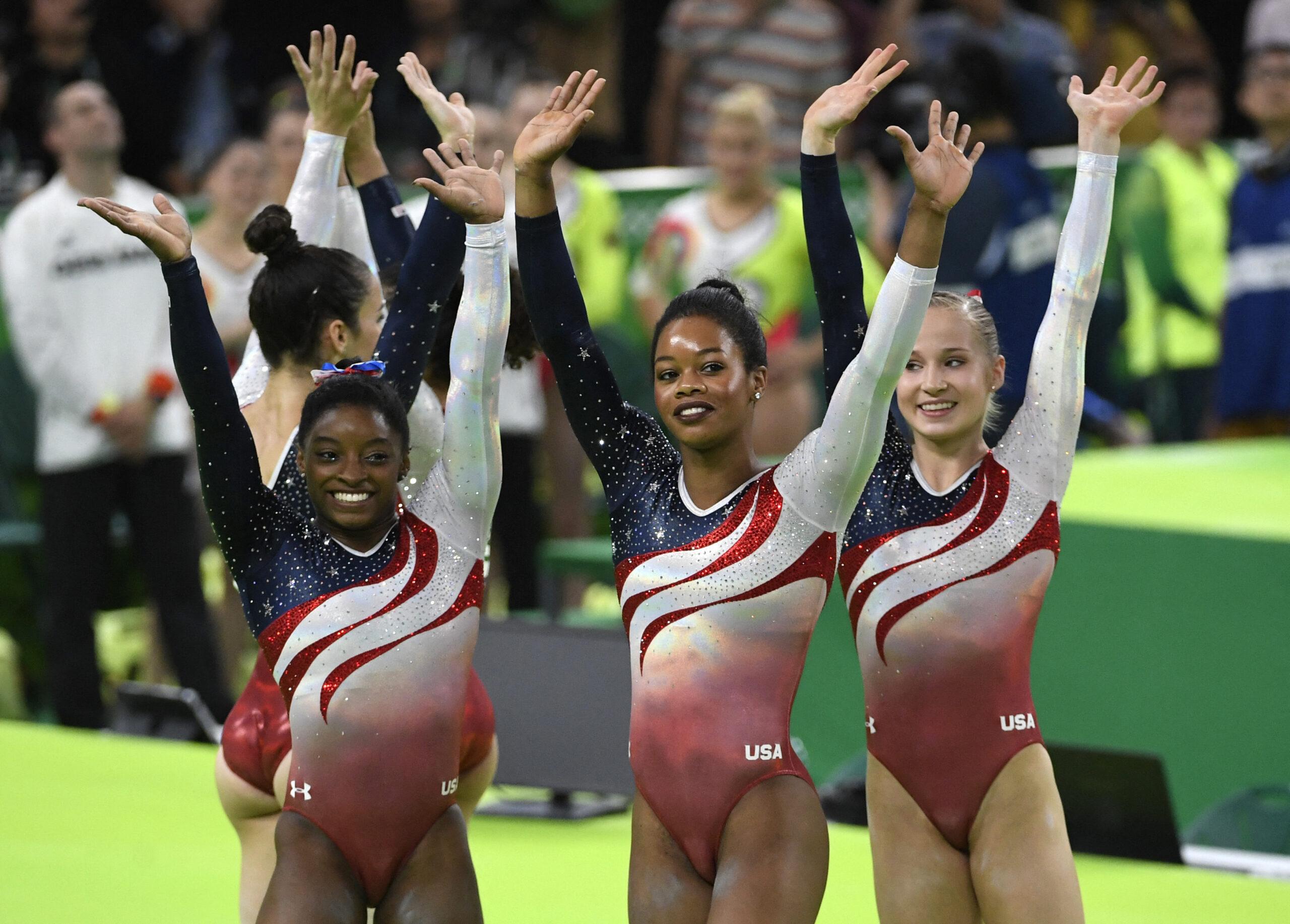 As ginastas Simone Biles, Gabby Douglas e Madison Kocian acenam para a multidão ao ganharem a medalha de ouro nas finais por equipes de ginástica artística feminina